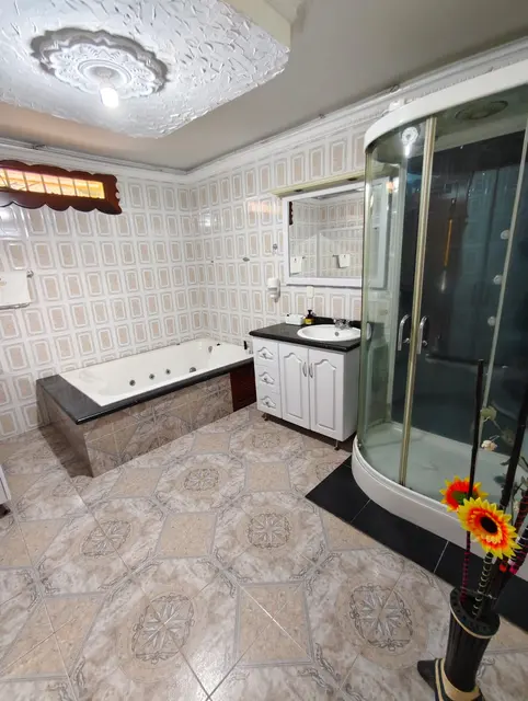 Baño amplio equipado con jacuzzi, ducha y tocador