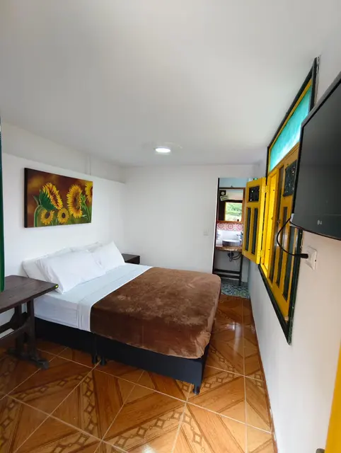 Habitación luminosa con cama doble, televisor y acceso al baño