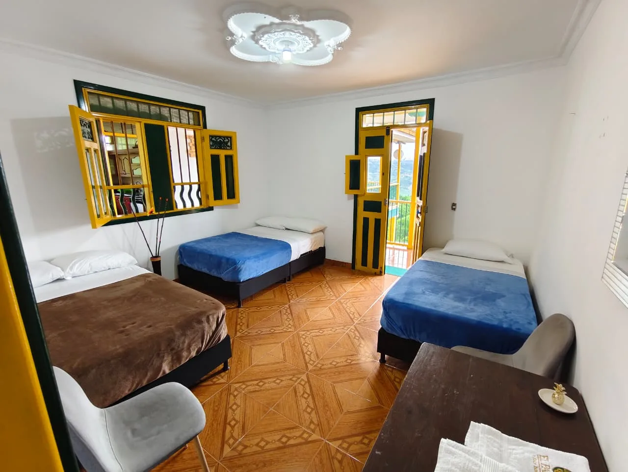 Habitación múltiple con tres camas, balcón y luz natural